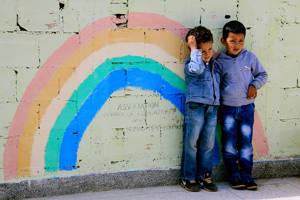Children standing by a rainbow on a wall that symbolises hope